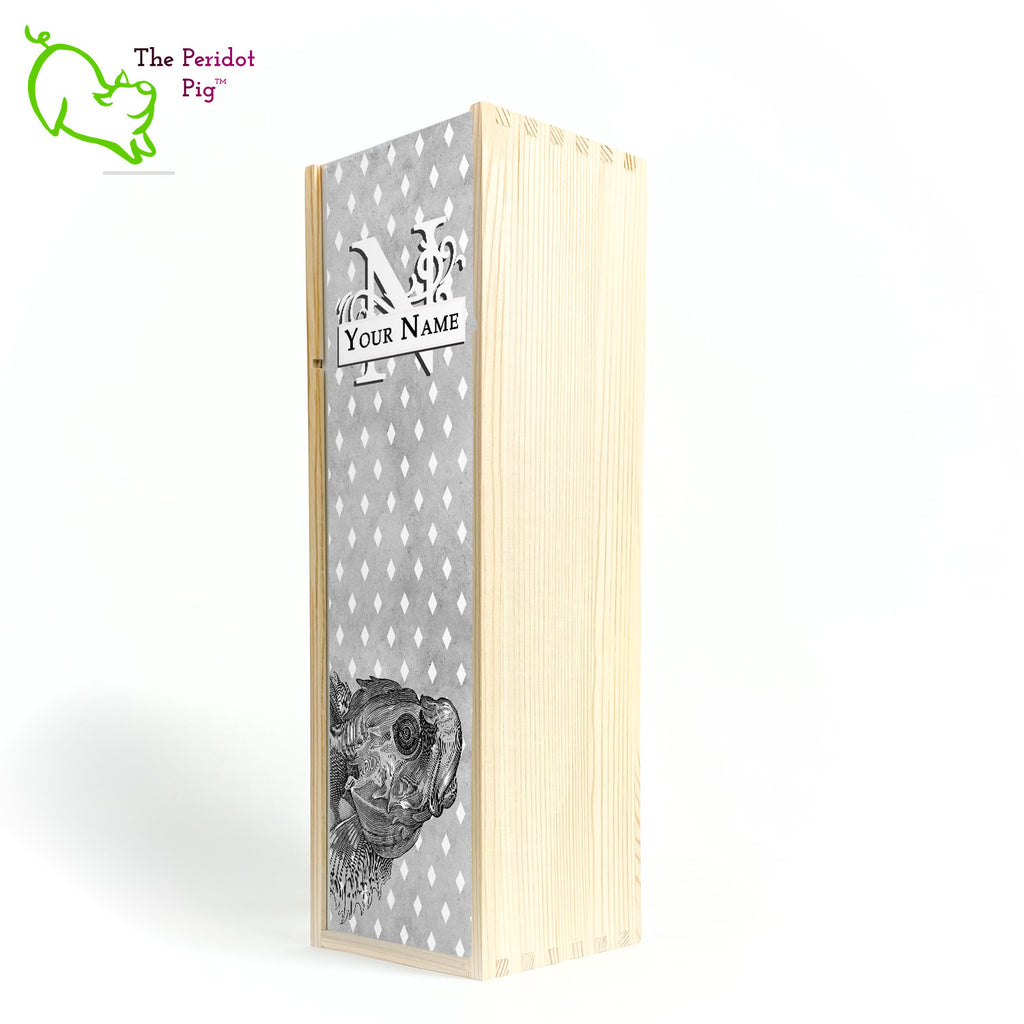 The wine box front panel is decorated in a glossy, detailed print with a white monogram and space for a customized name. This model has a smokey gray background with a pattern of white diamond shapes. In the foreground is a large black line drawing of a fish. Cherry finish showing the front view.