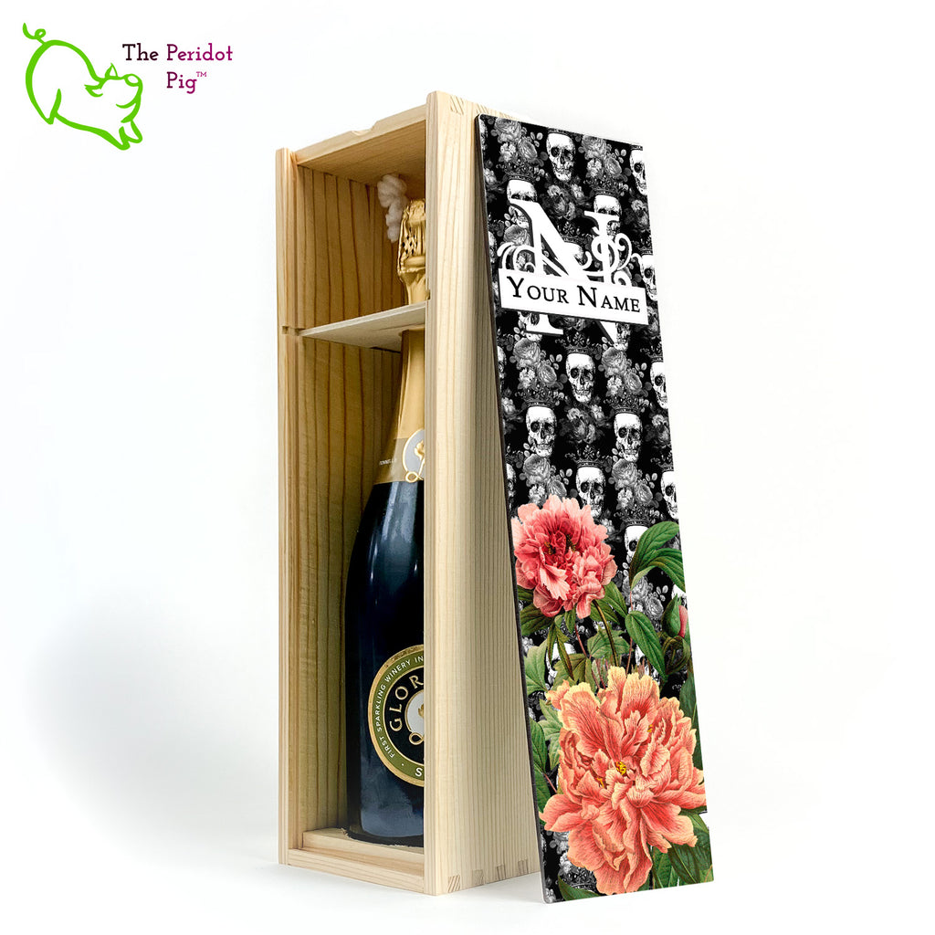 The front panel is decorated in a glossy, detailed print with a monogram and space for a customized name. This model has a background of Victorian skulls wearing a crown. in the foreground, there are two colorful peonies with green foliage. Front view in natural showing the interior of the box and a sample bottle of wine.
