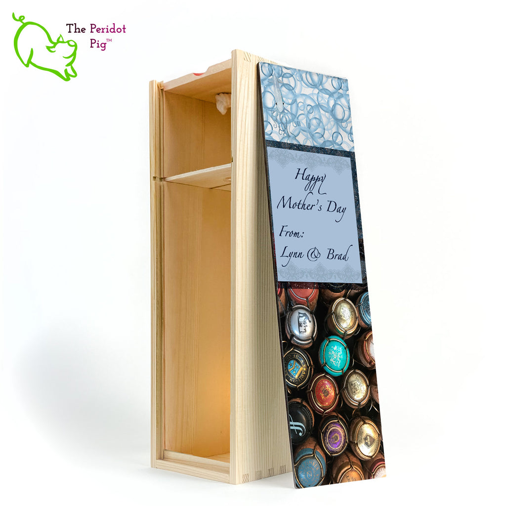 The wine box front panel is decorated in a glossy, detailed print with a space for a customized name(s) and/or a date. This model has a colorful picture of champagne corks on the bottom. The center frame features a field of blue with antique lace and flowing script.  We warned you that we were hiding another little squid and you'll see him peaking from the bubbles at the top of the panel! Example Mother's Day in natural.