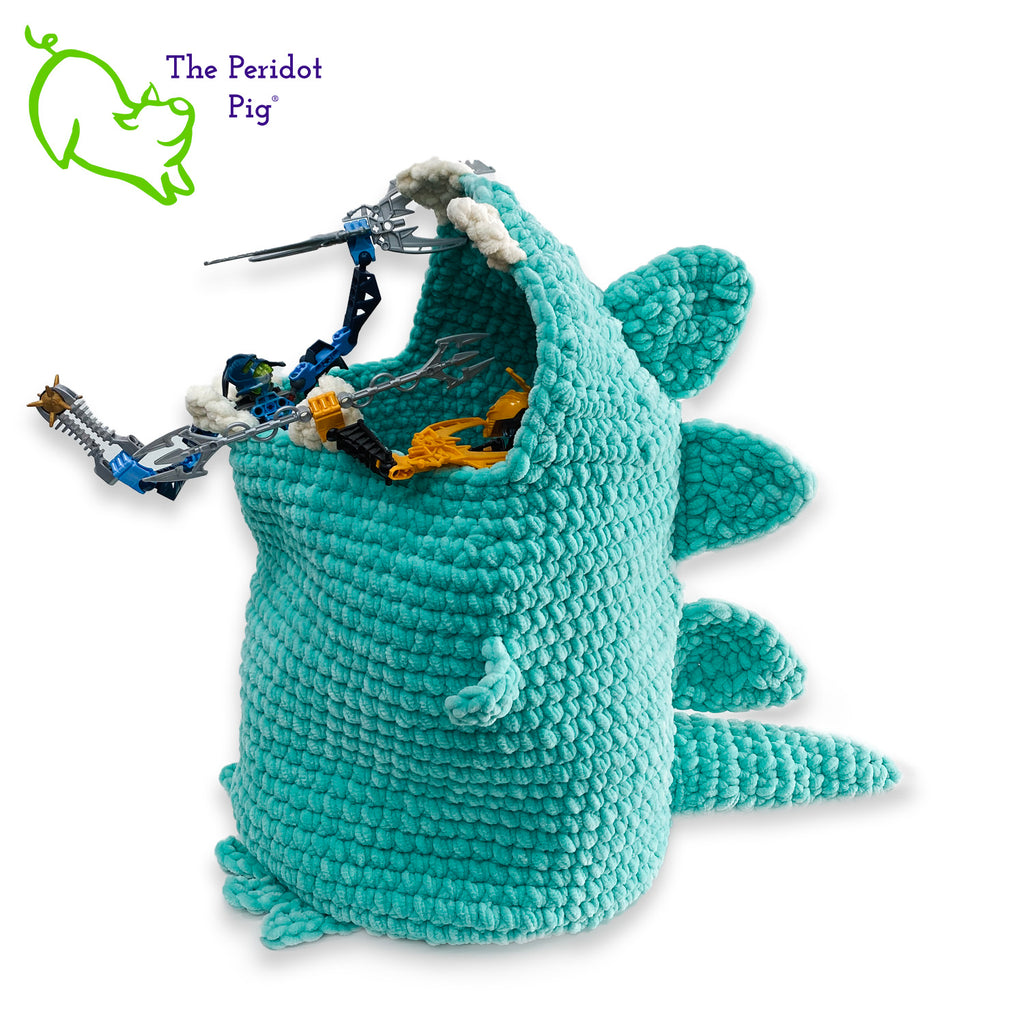 Hear Tiffany roar! Luckily she looks more menacing than reality. She's soft and plush from being made with a soft poly chenille. She just wants a hug but she has these little tiny arms which make it hard. Even her teeth and spikes are soft! As you can see, Tiffany has a big mouth that can hold a lot of toys, towels, clean diapers, even toilet paper (we put in 9 double rolls!). Left view shown filled with toys.