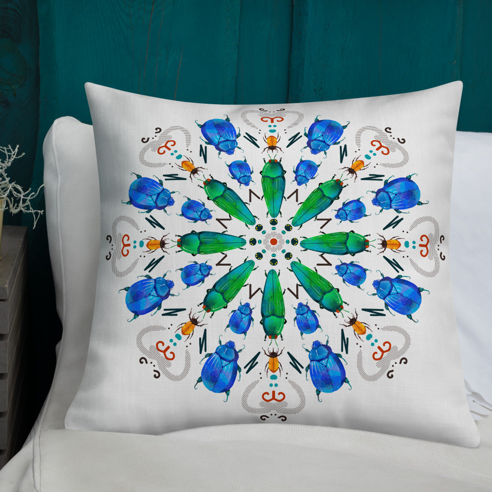 A colorful mandala of beetles graces this white pillow and is availble in either 18"x18" or 22"x22" sizes. The image is printed on both the front and back. The center beetles have shades of bright green. The smaller beetles are blue and orange. 22" front view shown on a bed.